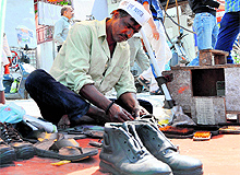 A cobbler wearing AAP cap mends shoes in Dehradun on Tuesday