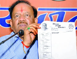 Delhi BJP president and Lok Sabha candidate from Chandni Chowk Dr. Harsh Vardhan displays a voters slip bearing the campaign advertisement of Congress candidate Kapil Sibal, claiming that this was against the Code of Conduct, in New Delhi on Thursday.