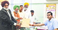 Rajat Aggarwal, District Electoral Officer-cum-Deputy Commissioner (right) accepts the nomination papers from CPI (M) candidate Sukhvinder Singh Sekhon (with garlands) in Ludhiana on Thursday.
