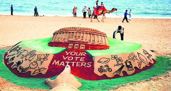 Sand artist Sudarsan Pattnaik creates an election-related sculpture at Puri beach on Saturday. PTI