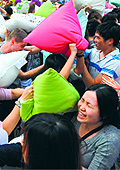People hit each other with pillows during the fourth international pillow fight day in Hong Kong on Saturday. Hundreds of people formed a sea of pillows as they went at each other