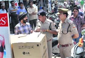 Policemen challan a shopkeeper near Clock Tower in Dehradun on Sunday