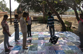 Support women to climb a ladder: Men playing a game of snakes and ladders during a campain launch activity in Pune, Maharashtra
