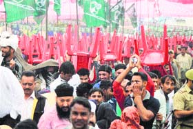 People hold chairs upside down to protect themselves from rain during a PDP rally in Jammu on Sunday