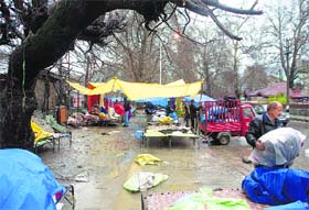 Roadside vendors at the Sunday market pack their stuff due to rain in Srinagar