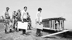 Polling officers carry EVMs at Laika Dodhiya in Tinsukhia district of Assam on Sunday