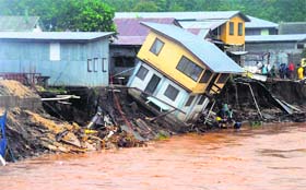 A building teeters on the edge of a river in Honiara, Solomon Islands. Flash floods in the Solomon Islands have killed 14 persons and left thousands more homeless.