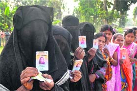 Voters hold their voter IDs outside a polling booth at Koliabor in Nagaon district of Assam on Monday
