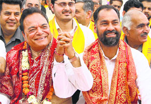 Congress candidate from Jalandhar (Reserved) constituency Chaudhary Santokh Singh (left) and his SAD-BJP rival Pawan Kumar Tinu share greetings during a religious function in Jalandhar on Tuesday.