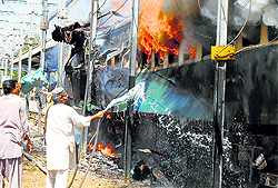 A Pakistani railway official extinguishies fire after a bomb blast on a train at the Sibi railway station on Tuesday