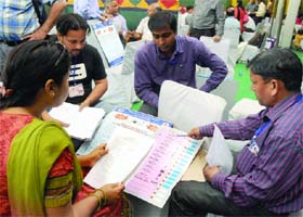 Polling officials check documents at a distribution centre before leaving for the booths on the eve of the Lok Sabha elections, at N.P. Bengali Girls Sr. Sec. School in New Delhi on Wednesday