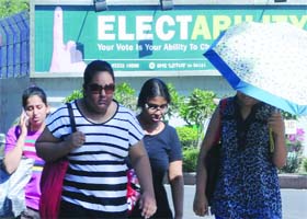 Girls pass by a voter awareness billboard alongside a road in New Delhi on Thursday