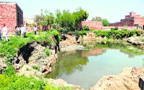 Dirty water accumulates in a pit created due to illegal excavation of land in Gillwali village in Amritsar