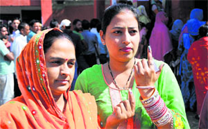 A newlywed woman shows her ink-marked finger after casting her vote at a polling station in Jammu on Thursday