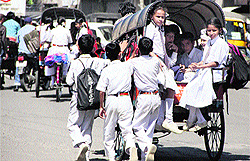 Schoolchildren move along an overloaded rickshaw while returning home from school in Jalandhar on Thursday