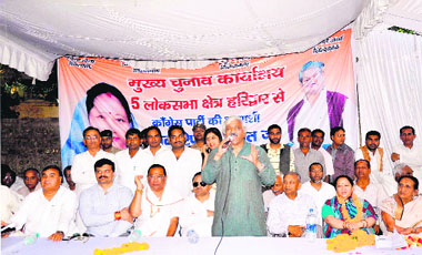 Sports Minister Dinesh Aggarwal addresses party workers as Congress candidate Renuka Rawat looks on, at the opening of party election office at Devpura in Haridwar on Saturday.
