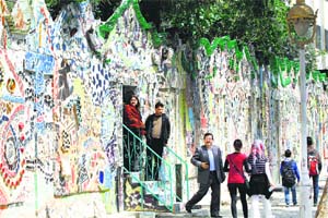 Syrians walk through a decorated wall that won the Guinness World Records award for the largest mural made from recycled material in Damascus’ al-Mazzeh neighbourhood