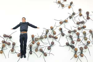 Colombian artist Rafael Gomezbarros poses for a photograph, alongside his work "Casa Tomada" made of resin, fibreglass, wood, screen cotton, rope and Cerrejon coal during a press preview of Pangaea: New Art from Africa and Latin America at the Saatchi Gallery in London