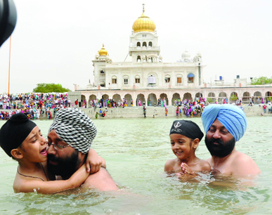 Devotees take a dip in the holy sarovar at Bangla Sahib Gurdwara at Baisakhi in New Delhi .