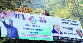 A woman walks on a path dotted with hoardings of political parties in Shimla.