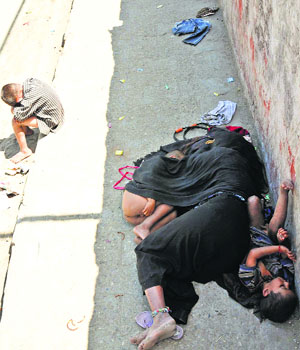 A homeless woman and her children rest on a footpath on the Canal Road in Jammu.
