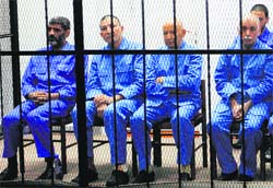 Officials of the erstwhile Muammar Gaddafis government sit behind bars during a hearing at a courtroom in Tripoli on Monday. Reuters