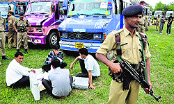 Security men stand guard as poll workers check electronic voting machines on the eve of the polling in Udhampur on Tuesday