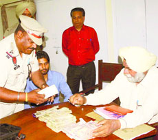 Static surveillance team along with police officials show Rs 18 lakh confiscated from a local resident travelling in a city bus on Wednesday.