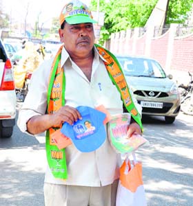 Poll paraphernalia Party: A man sells Congress' caps, BJP's scarf and stickers along with BSP caps at Gandhi Road in Dehradun on Wednesday