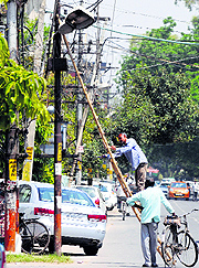 Workers repair a streetlight as temperature soars in Ludhiana