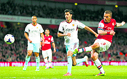 Arsenal's Lukas Podolski shoots to score his second goal against West Ham United during their English Premier League match in London on Tuesday