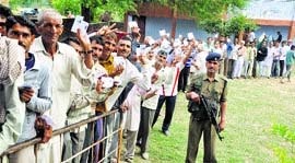 People display their voter I-cards as they wait to cast their ballots at Ladwal border village in Kathua district on Thursday.