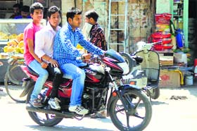 Youths indulge in triple riding on a motorcycle without wearing crash helmets at Gole Market in Jammu.