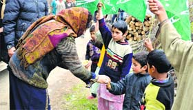 PDP president Mehbooba Mufti distributes sweets among children during a rally in Anantnag district on Thursday.