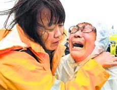 Relatives of a passenger aboard a sunken ferry cry as they wait for the news on the rescue operation, at a port in Jindo on Thursday