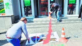An activist paints a symbolic blood stain going from the flag of the Donetsk Republic militia to the entrance of the Russian Sberbank branch in Kiev during a protest on Friday.