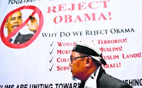 A Malaysian Muslim activist walks past a banner during a protest against US President Barack Obama's upcoming visit to Malaysia, outside the US Embassy in Kuala Lumpur, on Friday.