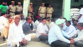 Traders sit on a dharna in the Kalanwali grain market of Sirsa on Saturday.