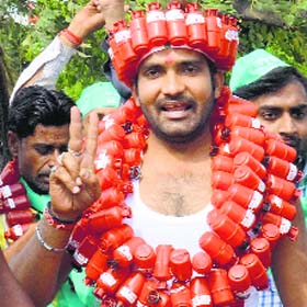 Independent candidate Shailendra Singh, wearing garland of replicas of LPG cylinders, campaigns in Lucknow on Saturday