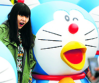 A visitor poses for a photo next to a Doraemon model during an exhibition which opened in Beijing on Saturday