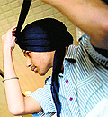 A young competitor looks in a mirror as he takes part in a turban tying competition in Surrey, Canada