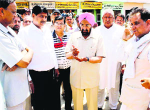 Finance Minister Harmohinder Singh Chatha inspects quality of wheat during his visit to the Pehowa Grain Market on Sunday.