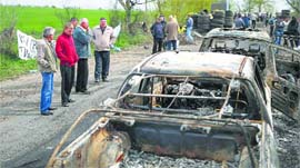 Local residents look at burnt cars near a checkpoint that was the scene of a gunfight near the city of Slaviansk, on Monday.