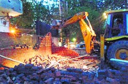 An illegal structure for a liquor vend in Model Town being razed by the MC staff in Jalandhar on Monday. A Tribune photograph