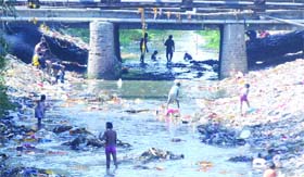 Children scavenge recyclable materials at Prem Badi drain on the World Earth Day, in North Delhi, on Tuesday
