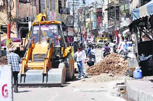 Municipal Corporation employees dig a road for laying sewer pipes at Rajinder Bazaar; and (right) the construction work of a flyover at Bikram Chowk also affects traffic in Jammu. 