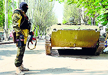 A man in military fatigues stands guard outside a security service building seized by separatists in Ukrainian city of Slavyansk