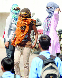 Girls cover their faces to beat the heat as the temperature reaches 38C in New Delhi on Thursday