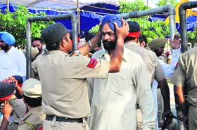 A visitor argues with a police official as he frisks his turban