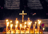 Candles and an orthodox cross are seen in front of a memorial, dedicated to victims of the Chernobyl nuclear disaster, during a night service in Kiev on Saturday